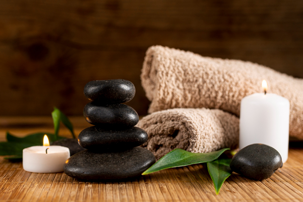 Svarta stenar för hot stone massage samt två beige handdukar och vita ljus!